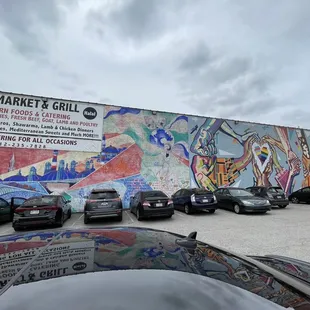 cars parked in front of a mural