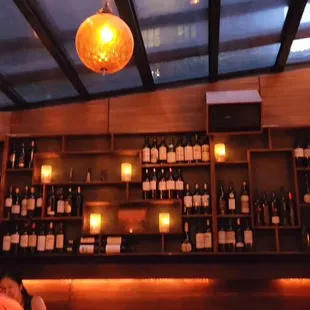 a man sitting at a bar with bottles of wine