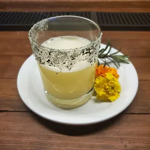 a glass of lemonade and a flower on a plate