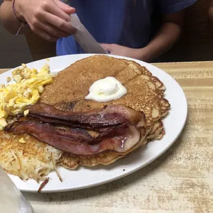 a plate of pancakes with bacon and eggs