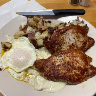 Two over easy eggs, with pork chops, and home fries.