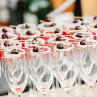 a row of wine glasses filled with cherries
