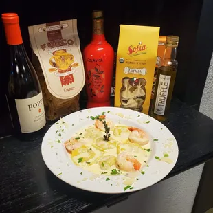 a plate of pasta and bottles of wine