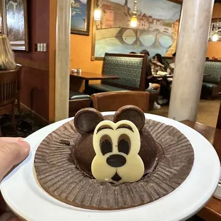 a person holding a plate with a mickey mouse cake on it