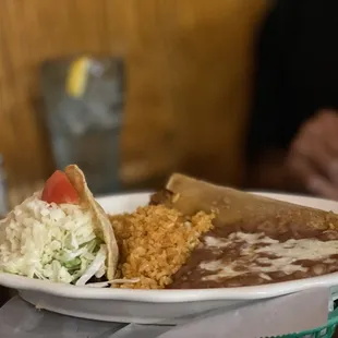 Crunchy taco and tamale plate with rice and beans.