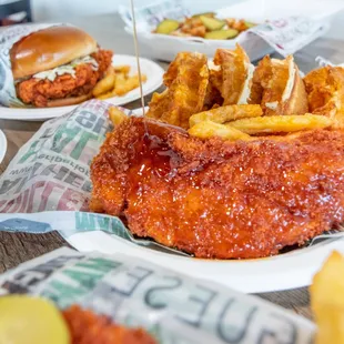 a hand drizzling sauce over a plate of fried chicken