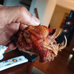 a hand holding a piece of bacon