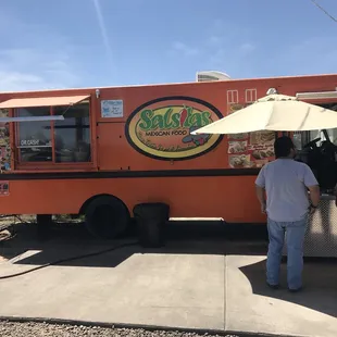 two people standing in front of a food truck