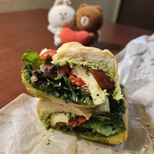 Tuscan Sandwich has arugula, tomato, pesto, red onion, roasted pepper, mozzarella