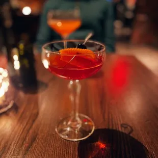 a man sitting at a bar with two cocktails