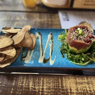 Tuna tartare: avocado, seaweed salad, sesame and ginger soy drizzle and wasabi aioli. Topped with sesame seeds and green onion.