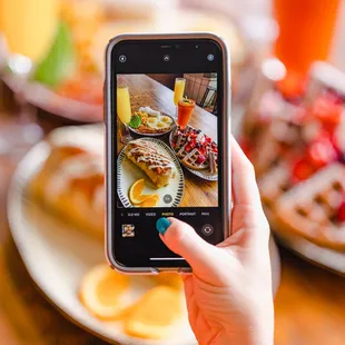 a person taking a picture of a plate of food