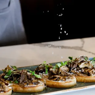a person sprinkling salt on a plate of food