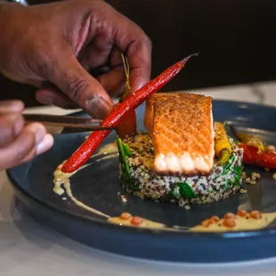 a person cutting a piece of fish on a plate