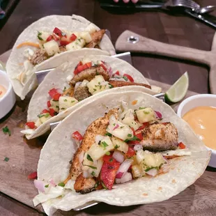 three fish tacos on a cutting board