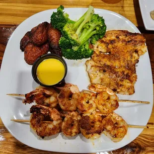 Blackened grouper with two grilled shrimp sticks, plantains, and garlic broccoli.