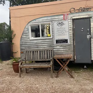 a coffee trailer with a bench in front of it