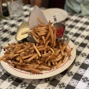 a plate of french fries on a checkered tablecloth
