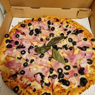 This is a large pizza with ham, black olives, onions, and light pizza sauce.