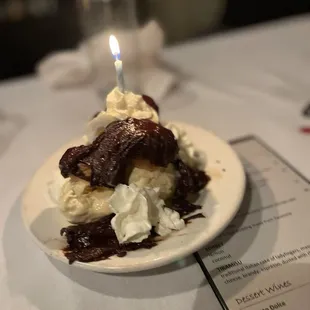 Profiteroles covered in chocolate layered with vanilla ice cream and a birthday candle!  That chocolate is rich &amp; decadent!