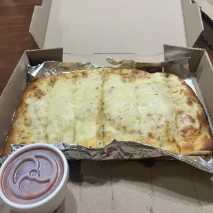 a pizza in a box with a side of ketchup