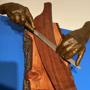 Sculpture of Sam&apos;s hands at work on a chair arm.