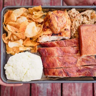 Ribs, chicken and pork tray with chips, coleslaw and cornbread at Sam Jones BBQ.