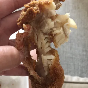a hand holding a half eaten chicken and fish