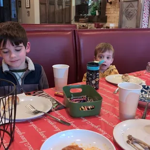 two children sitting at a table with plates of food