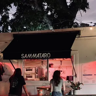 two people standing in front of a food truck