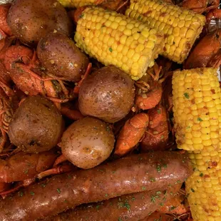 a tray full of cooked crawfish, corn and potatoes