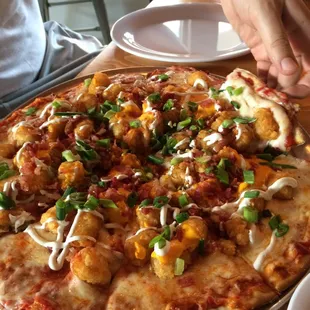 Order a cheese pizza and a order of Tot-Chos, then ask them to put the Tot-Chos on the pizza. Its heavenly!