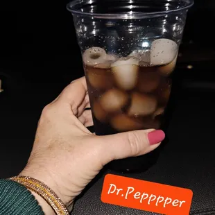 a person holding a plastic cup of ice tea