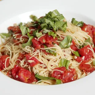 a plate of spaghetti with tomatoes and basil