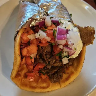 Gyro wrapped in grilled pita stuffed with tomatoes, onions, and tzatziki sauce.
