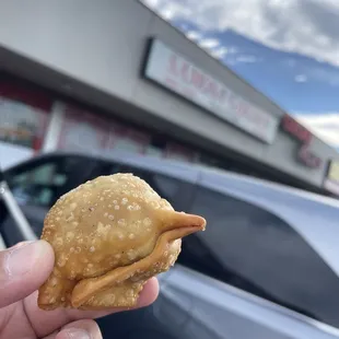 a hand holding a sandwich in front of a store