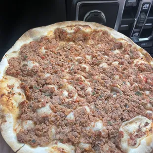a hand holding a pizza