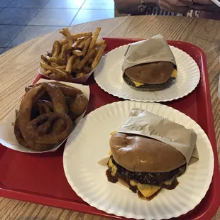 Onion rings, seasoned fries, a Chili cheese burger plain, and a cheese burger with just pickles