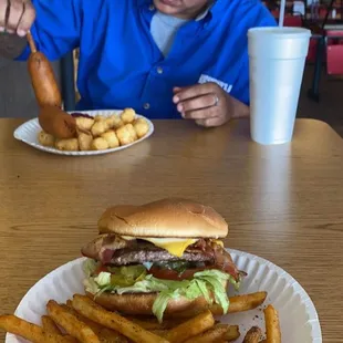 a man eating a hamburger and fries