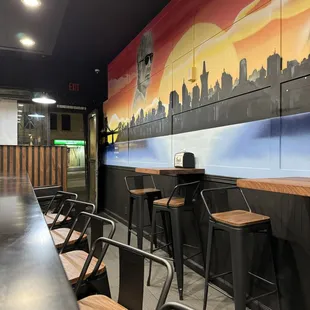 a row of bar stools in front of a mural