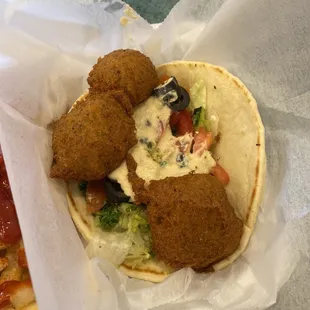 Falafel on pita bread, with hummus, lettuce, tomatoes, black olives, and tabbouleh.