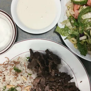 Meat shawarma with rice and salad also a side of the garlic sauce