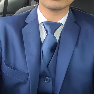 Man wearing a blue suit jacket, a blue vest, blue tie, and white shirt.