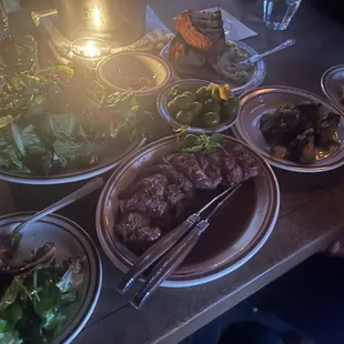 Counter clockwise: rosette plate, herb salad, steak, Japanese sweet potatoes, marinated olive in center