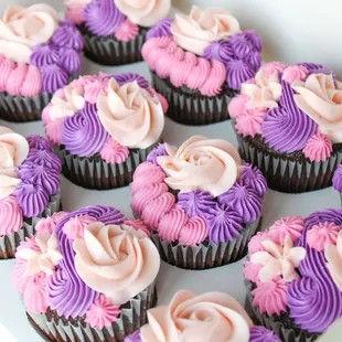 a plate of cupcakes with pink and purple frosting