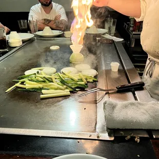 a man cooking on a grill with flames coming out of it