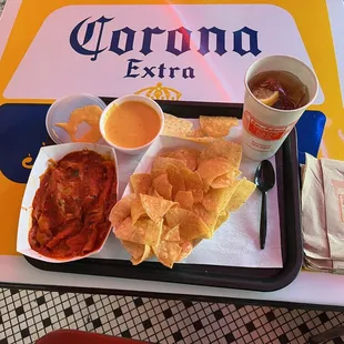 Beef enchiladas covered in mild sauce at left, chips and queso in center, and a Southern teetotaler&apos;s alternative to Corona at right.