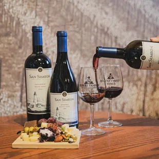 a person pouring red wine into a glass