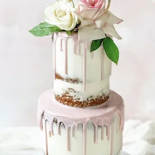 a three tiered cake with drips and flowers