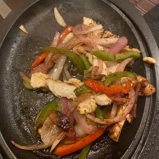 chicken, peppers, and onions cooking in a skillet